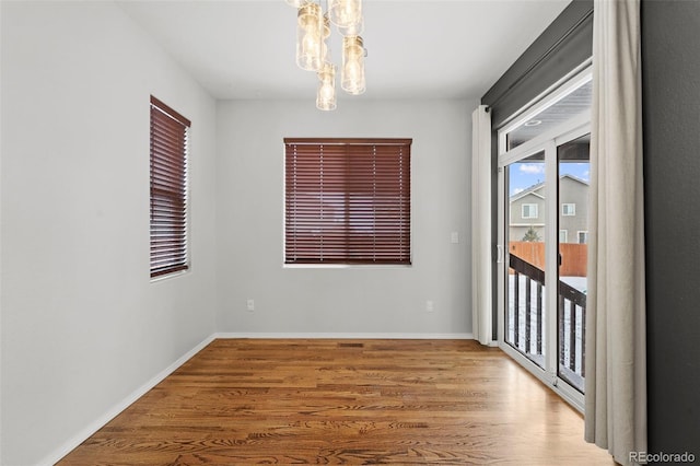 spare room with hardwood / wood-style floors and a notable chandelier