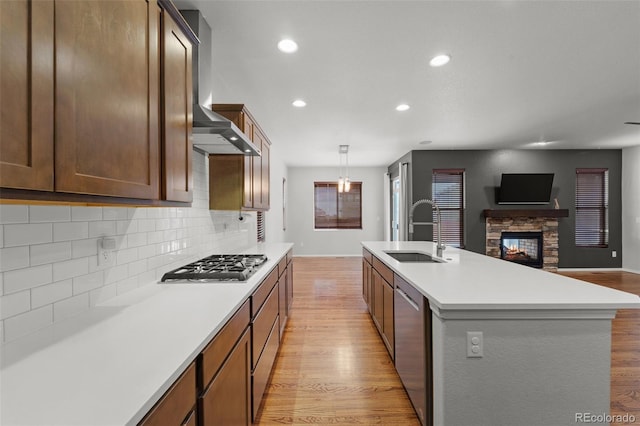 kitchen featuring backsplash, sink, a fireplace, appliances with stainless steel finishes, and an island with sink