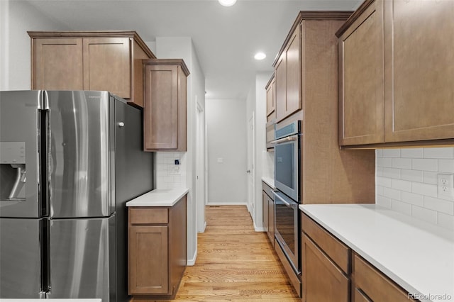 kitchen featuring light wood-type flooring, stainless steel fridge, and backsplash