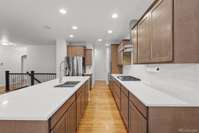 kitchen with stainless steel appliances, a kitchen island with sink, light hardwood / wood-style floors, and sink