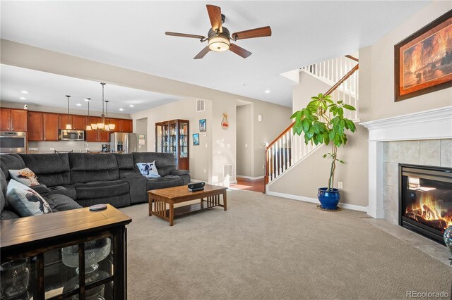 living room with a tile fireplace, recessed lighting, light carpet, baseboards, and stairs