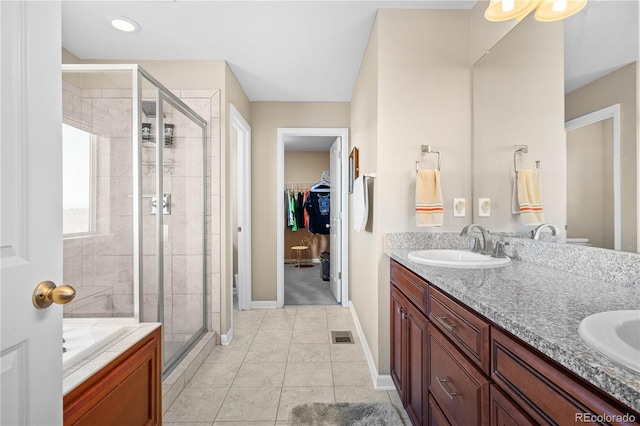 bathroom featuring double vanity, a stall shower, tile patterned floors, a spacious closet, and a sink