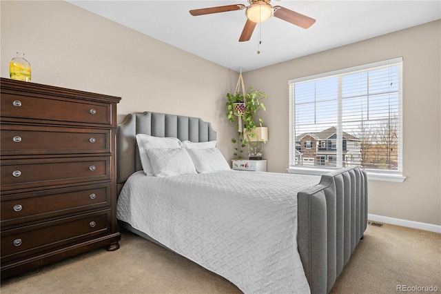 bedroom featuring light colored carpet, ceiling fan, visible vents, and baseboards