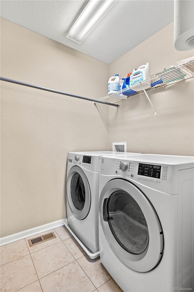 washroom with light tile patterned floors, laundry area, visible vents, baseboards, and washer and dryer