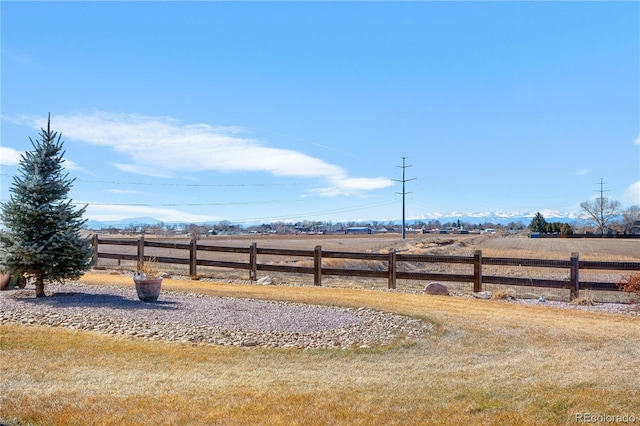 view of yard with fence and a rural view