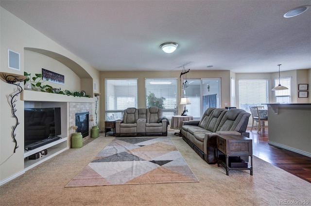 carpeted living room featuring a tiled fireplace and a textured ceiling