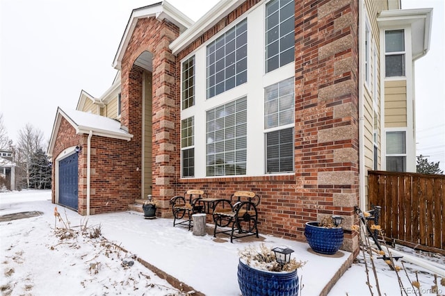 snow covered property with a garage