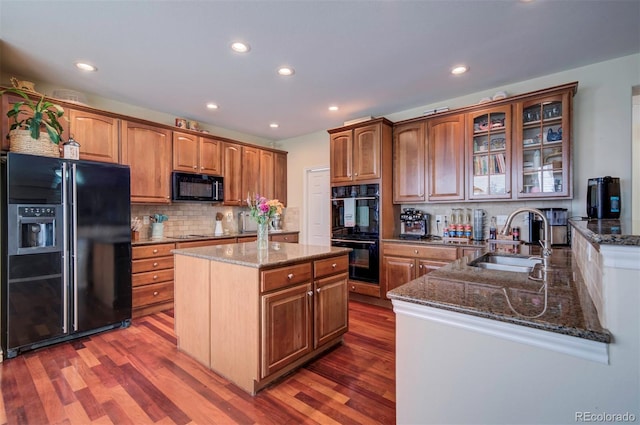 kitchen with hardwood / wood-style floors, sink, dark stone countertops, and black appliances