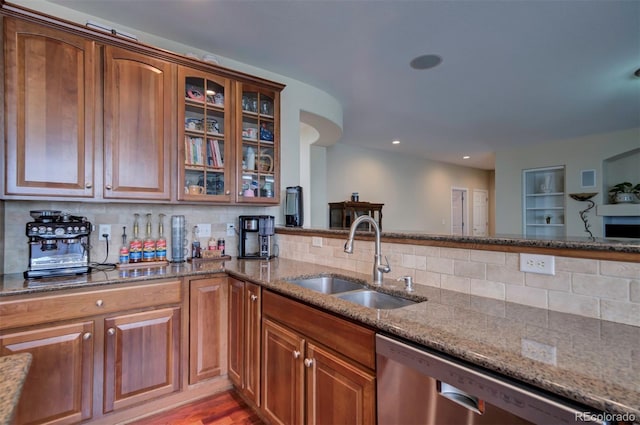 kitchen featuring sink, backsplash, stainless steel dishwasher, and dark stone counters