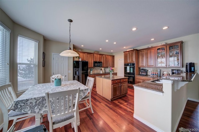 kitchen featuring decorative light fixtures, black appliances, sink, a kitchen breakfast bar, and kitchen peninsula