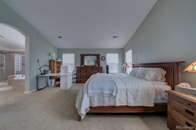 bedroom featuring lofted ceiling, light colored carpet, and ensuite bathroom