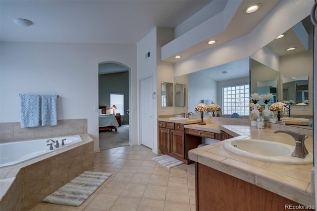 bathroom featuring vanity, tiled tub, and tile patterned flooring