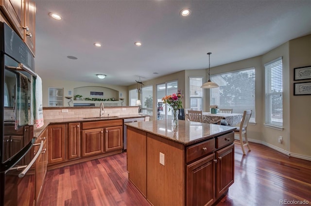 kitchen with sink, decorative light fixtures, a center island, double oven, and light stone countertops