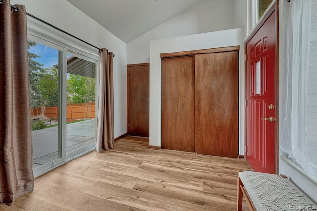 unfurnished bedroom with access to exterior, vaulted ceiling, and light wood-style floors