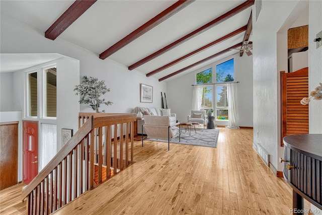 living room featuring beamed ceiling, light wood finished floors, high vaulted ceiling, a ceiling fan, and baseboards