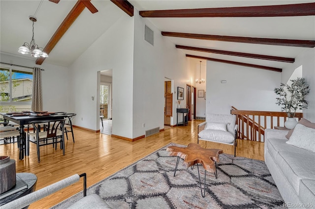 living room with a chandelier, beamed ceiling, light wood finished floors, high vaulted ceiling, and baseboards
