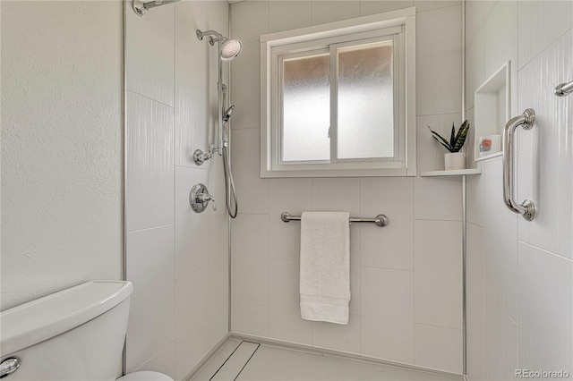 bathroom with a tile shower and toilet