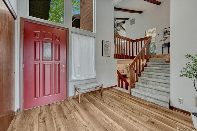 entrance foyer with a high ceiling, wood finished floors, beam ceiling, stairs, and baseboards