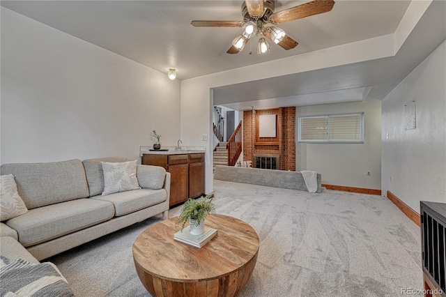living room featuring carpet flooring, ceiling fan, baseboards, and stairway