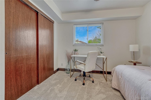 bedroom featuring light carpet, a closet, and baseboards