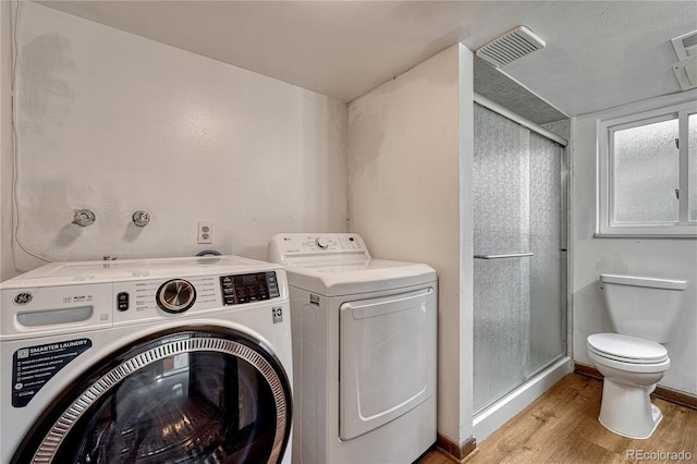 laundry area with washer and clothes dryer, wood finished floors, and baseboards