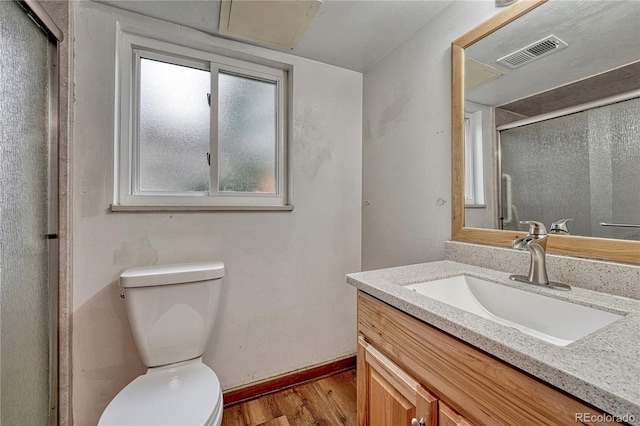 bathroom with wood finished floors, toilet, vanity, baseboards, and an enclosed shower