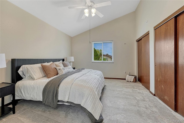 bedroom featuring light colored carpet, lofted ceiling, ceiling fan, baseboards, and multiple closets