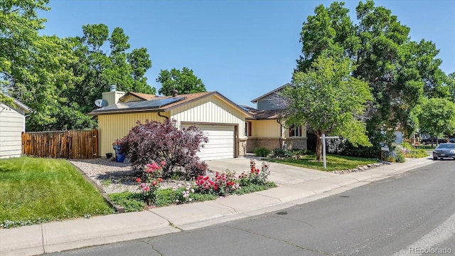 8705 W 86th Dr, Arvada, CO 80005 - view of front facade with solar panels, a garage, concrete driveway, and a chimney