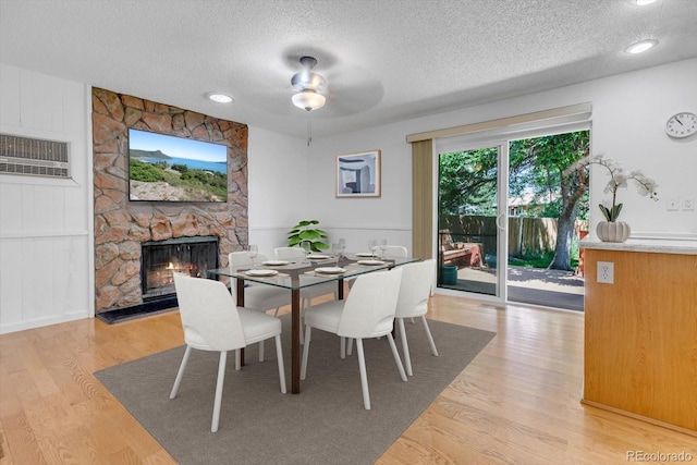 8705 W 86th Dr, Arvada, CO 80005 - dining area featuring a textured ceiling, a fireplace, a wall mounted air conditioner, light wood-type flooring, and ceiling fan