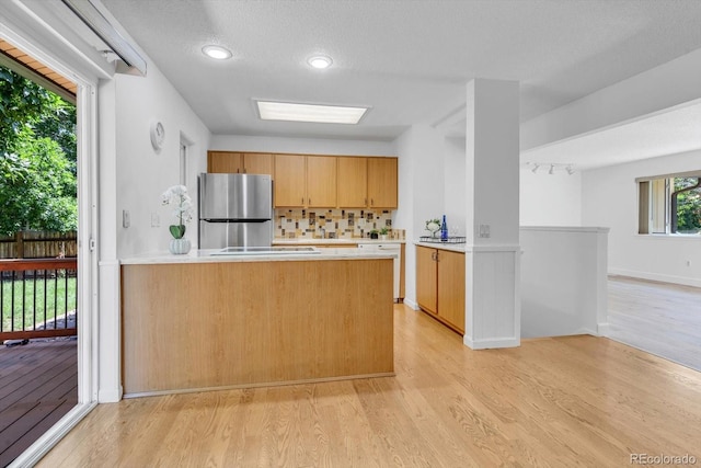 8705 W 86th Dr, Arvada, CO 80005 - kitchen with freestanding refrigerator, light countertops, light wood-type flooring, decorative backsplash, and a peninsula