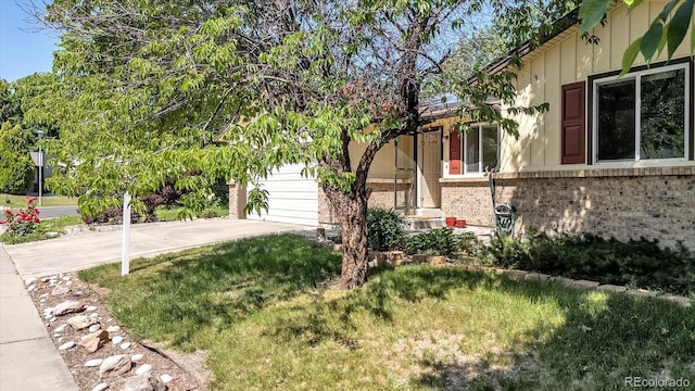 8705 W 86th Dr, Arvada, CO 80005 - view of home's exterior featuring concrete driveway, brick siding, a garage, and a lawn