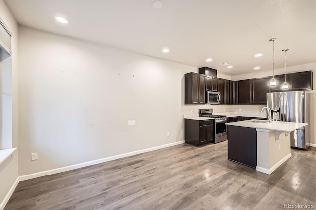 kitchen with light countertops, appliances with stainless steel finishes, light wood-style floors, a sink, and baseboards