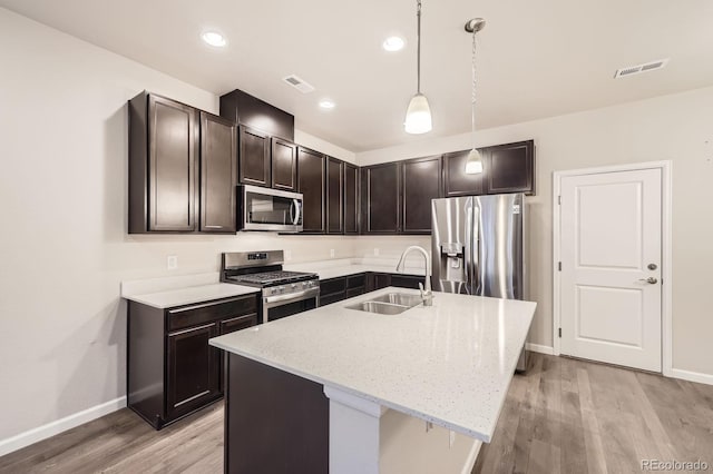 kitchen with stainless steel appliances, visible vents, a sink, and light stone counters