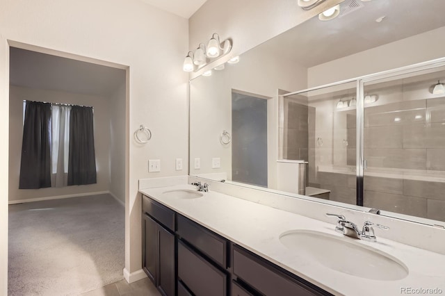 bathroom with baseboards, double vanity, a sink, and a shower stall