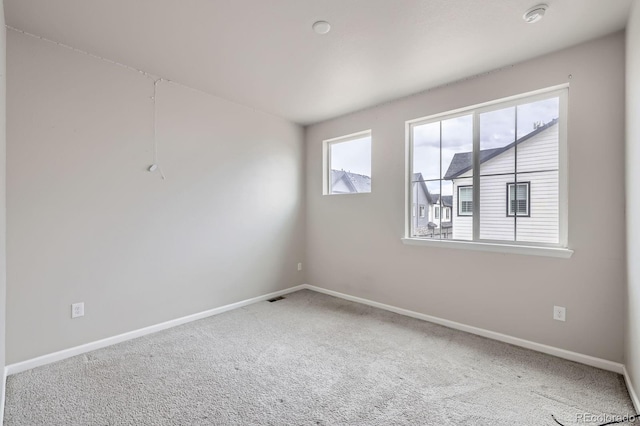 carpeted empty room featuring visible vents and baseboards