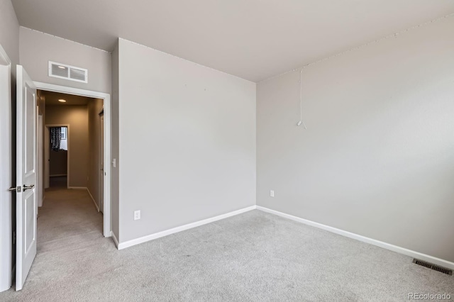 empty room featuring visible vents, light carpet, and baseboards