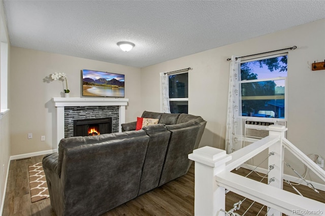 living room with a textured ceiling, a stone fireplace, and wood-type flooring