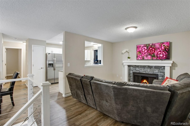 living room with hardwood / wood-style floors, a tiled fireplace, and a textured ceiling