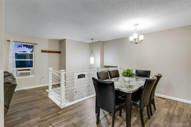 dining area with dark wood-type flooring, cooling unit, a textured ceiling, and an inviting chandelier