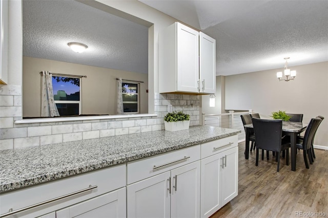 kitchen featuring light stone countertops, a textured ceiling, light hardwood / wood-style flooring, and white cabinets