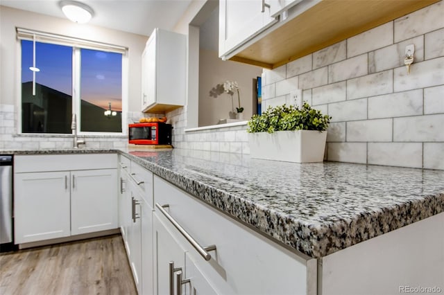 kitchen with backsplash, sink, white cabinets, light stone counters, and light hardwood / wood-style floors