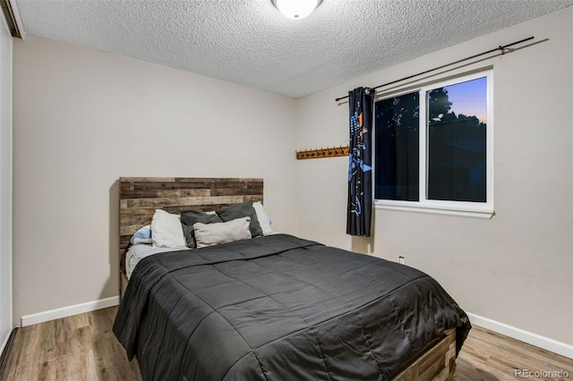 bedroom with a textured ceiling and hardwood / wood-style flooring