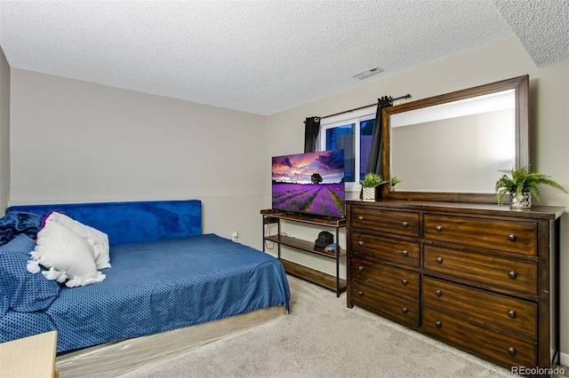 bedroom featuring a textured ceiling and light colored carpet