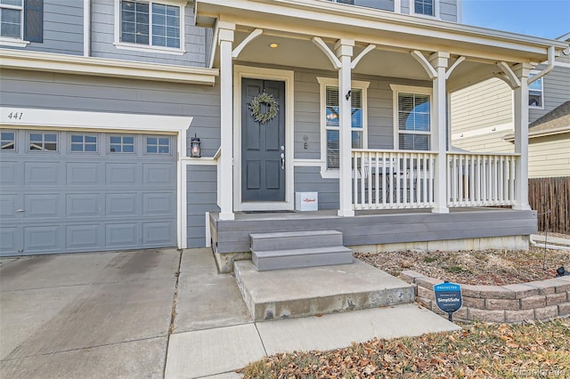 doorway to property with an attached garage, a porch, and concrete driveway