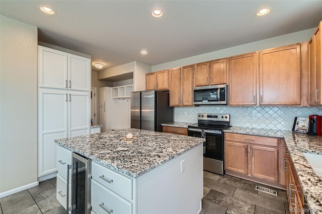 kitchen with beverage cooler, appliances with stainless steel finishes, and white cabinetry