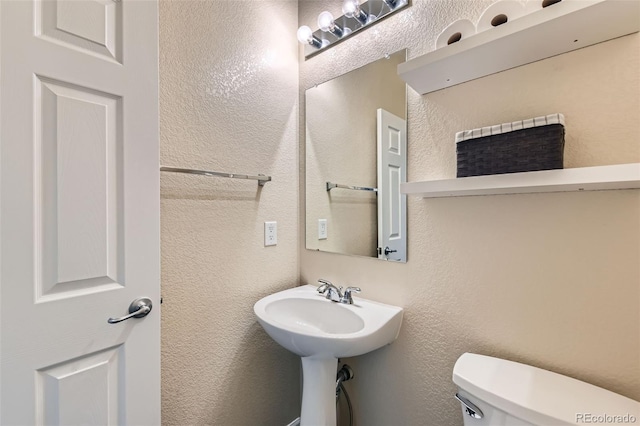 bathroom featuring a textured wall and toilet