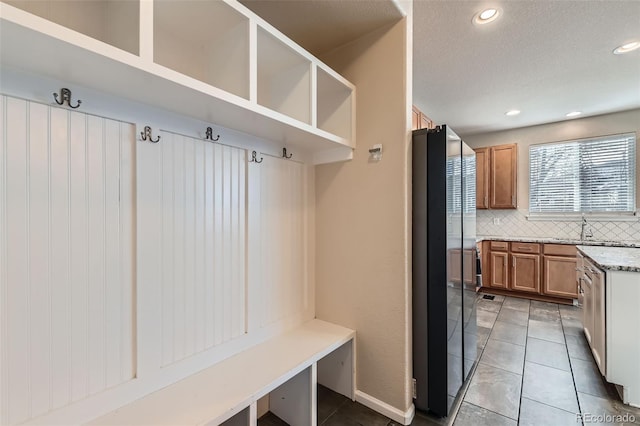 mudroom featuring light tile patterned floors, a textured ceiling, a sink, and recessed lighting