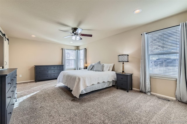 bedroom with light carpet, a barn door, visible vents, baseboards, and recessed lighting