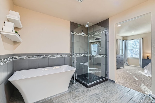 bathroom featuring a soaking tub, a shower stall, tile walls, and a wainscoted wall