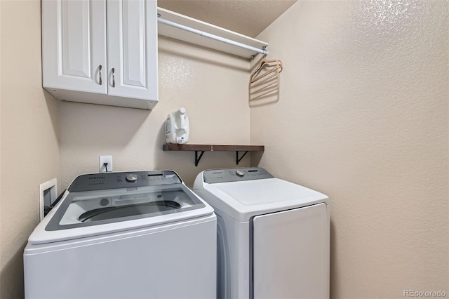 laundry room featuring cabinet space, a textured wall, and separate washer and dryer